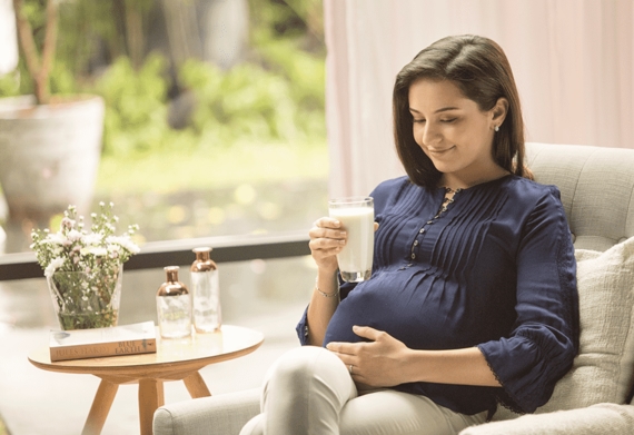 A mother holding a cup of maternal milk