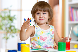 A toddler painting with his fingers