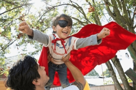 A child is playing super hero flying game with father