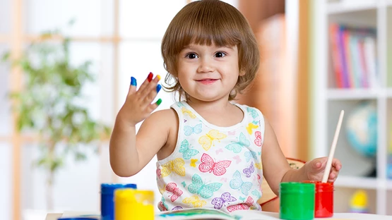 A toddler painting with his fingers