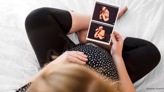 Pregnant Woman looking at her ultrasound scans showing monthly development of her fetus