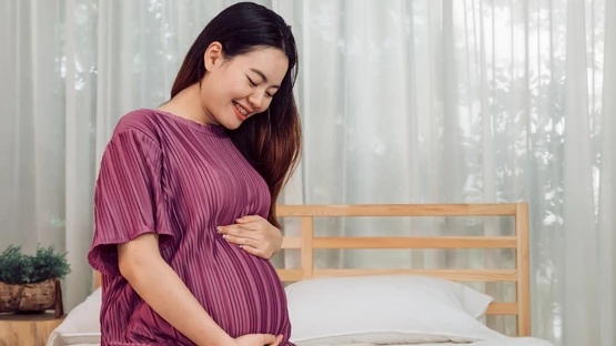 portrait-young-adult-asian-pregnant-woman-touching-her-belly-with-love-home Large.jpeg